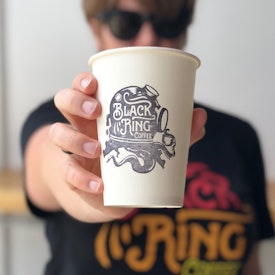 黒いロゴデザインが表示されているコーヒーカップ